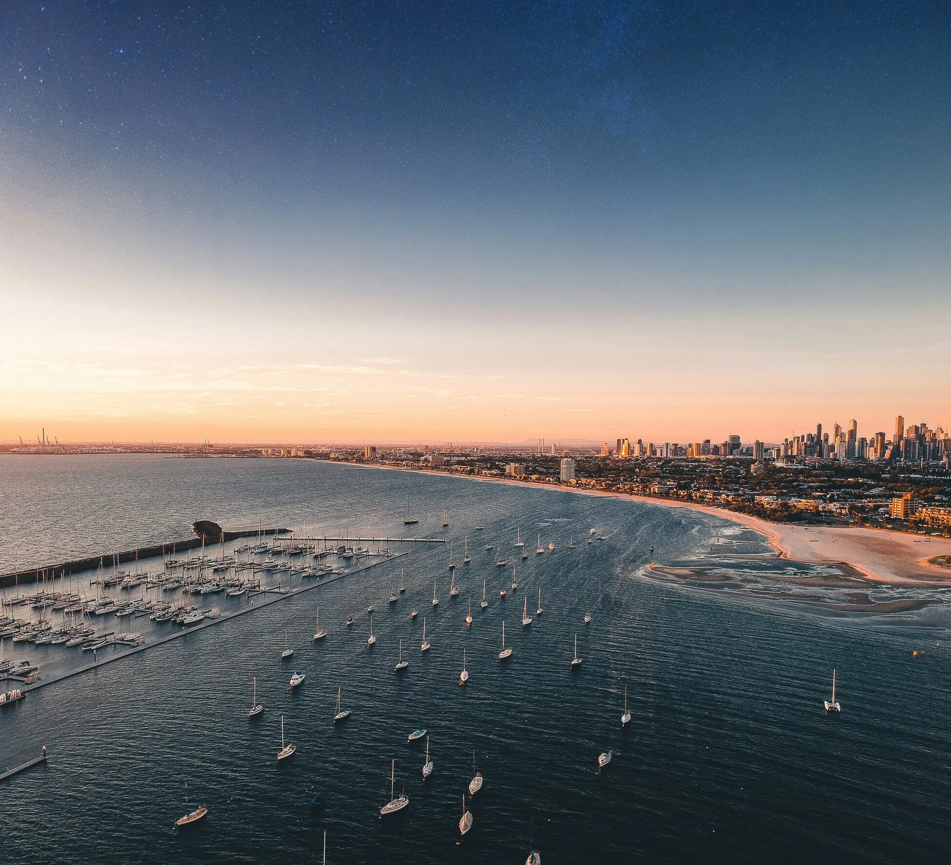 Aerial view of a Melbourne bayside marina and the city skyline at sunset