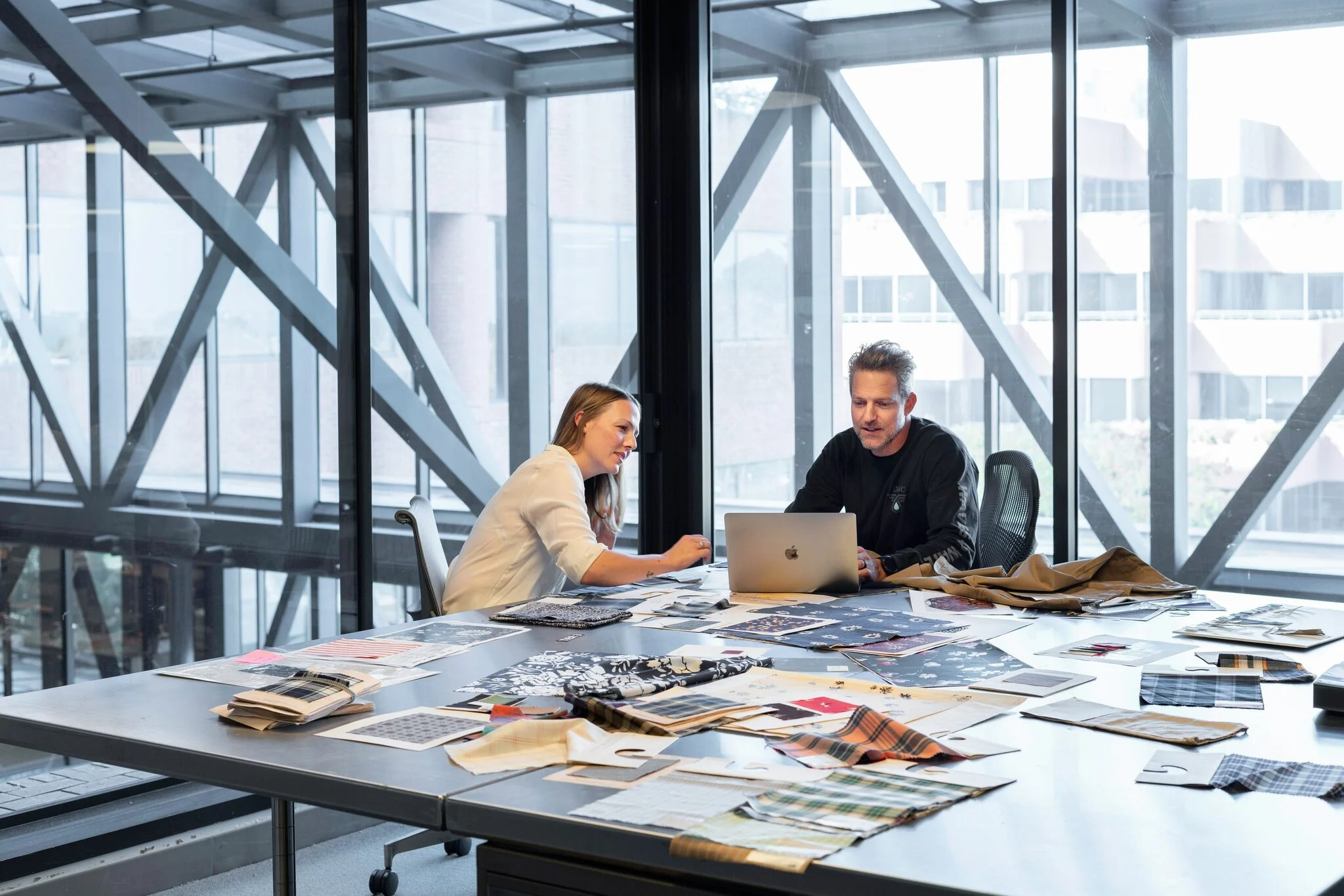 Two colleagues reviewing plans at a desk in a glass office
