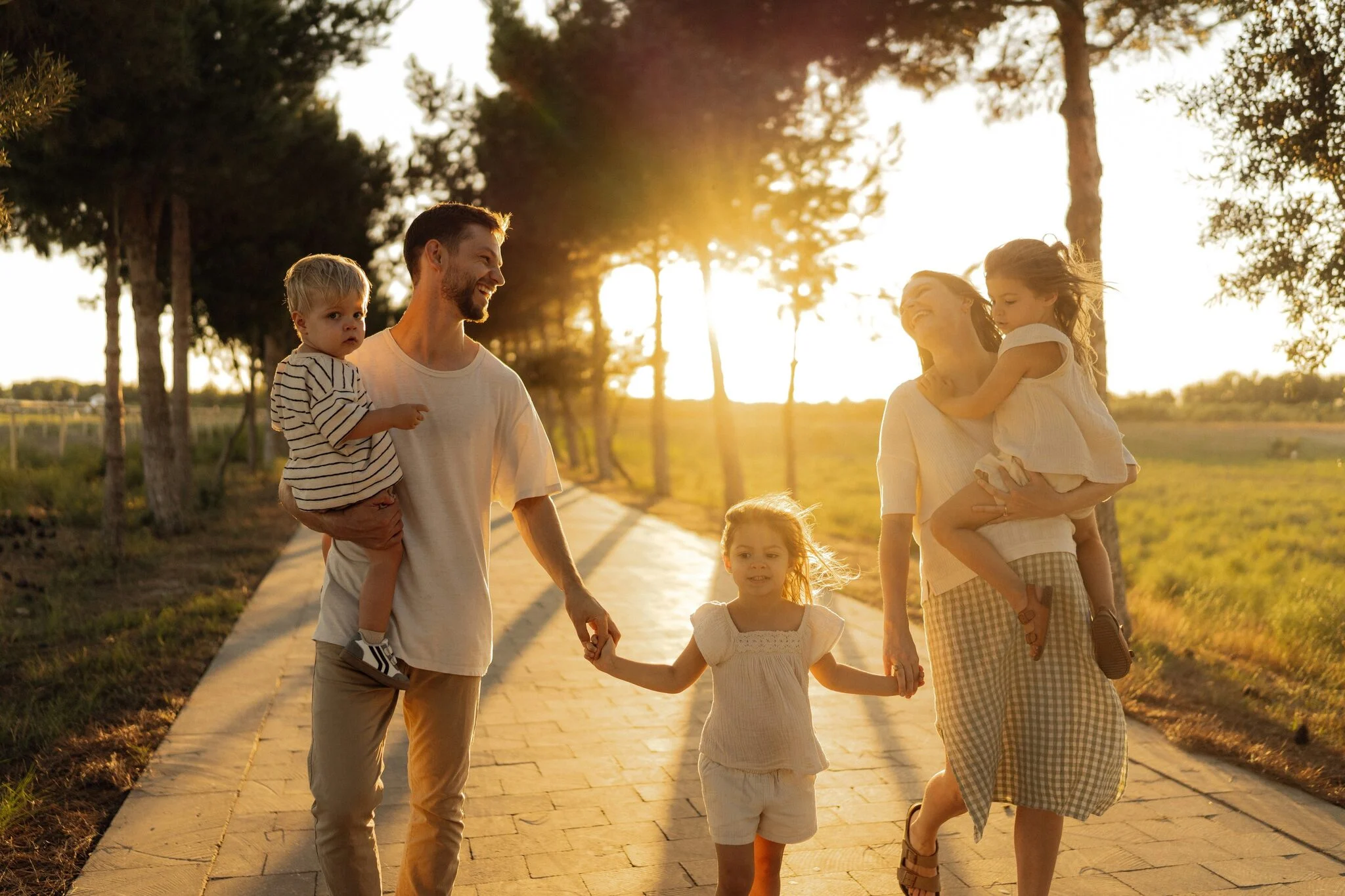 Family walking hand in hand along a country road at sunset
