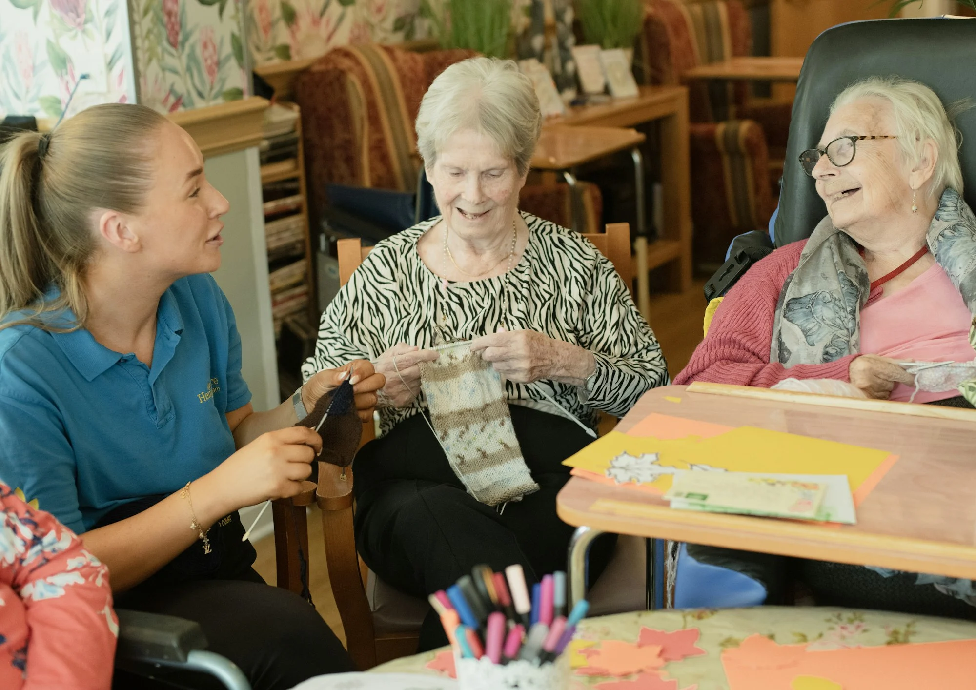 Care worker with elderly residents knitting together, aged care insurance for providers