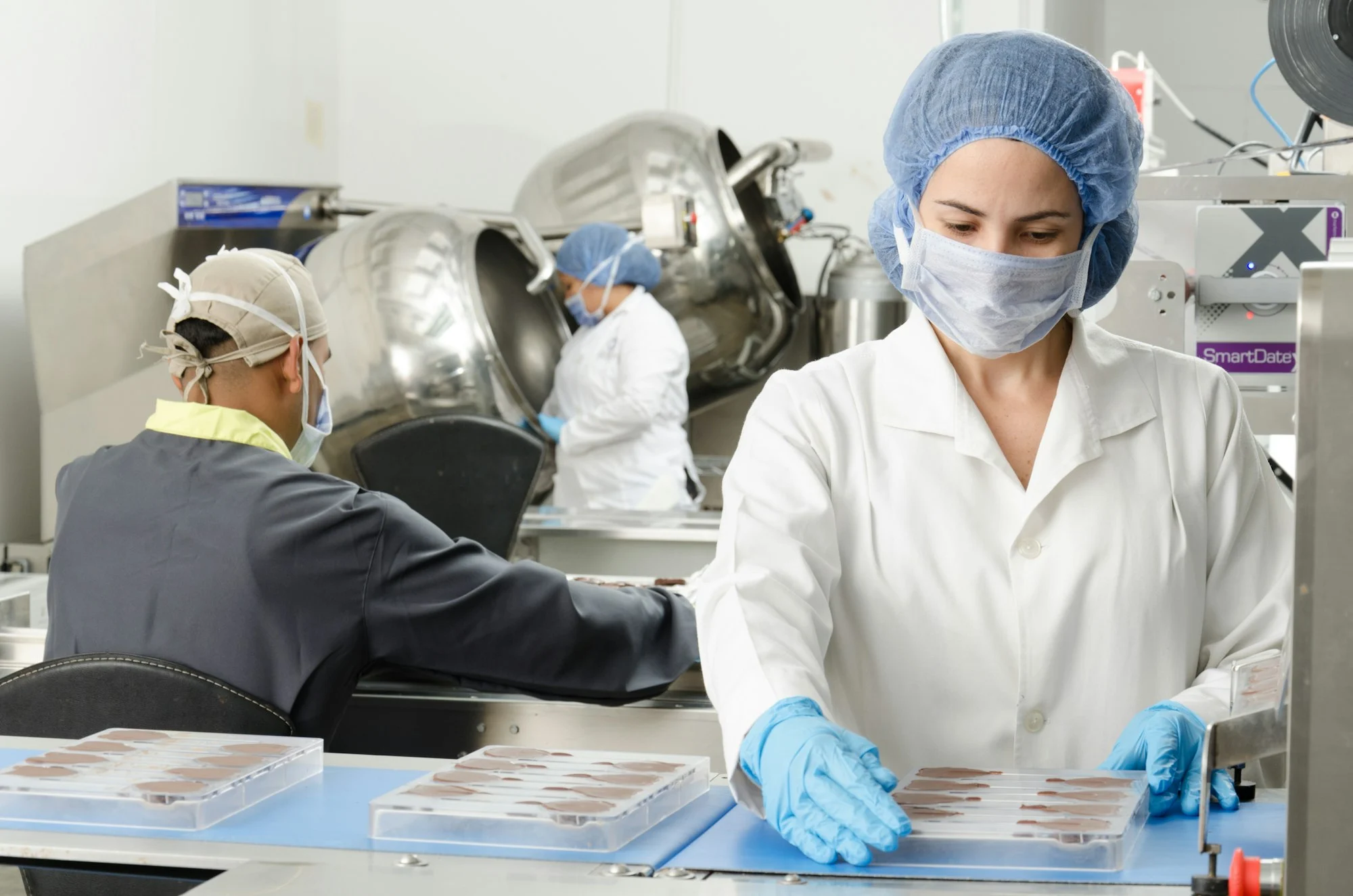 Food production staff in masks and hairnets at a processing line, food manufacturing insurance