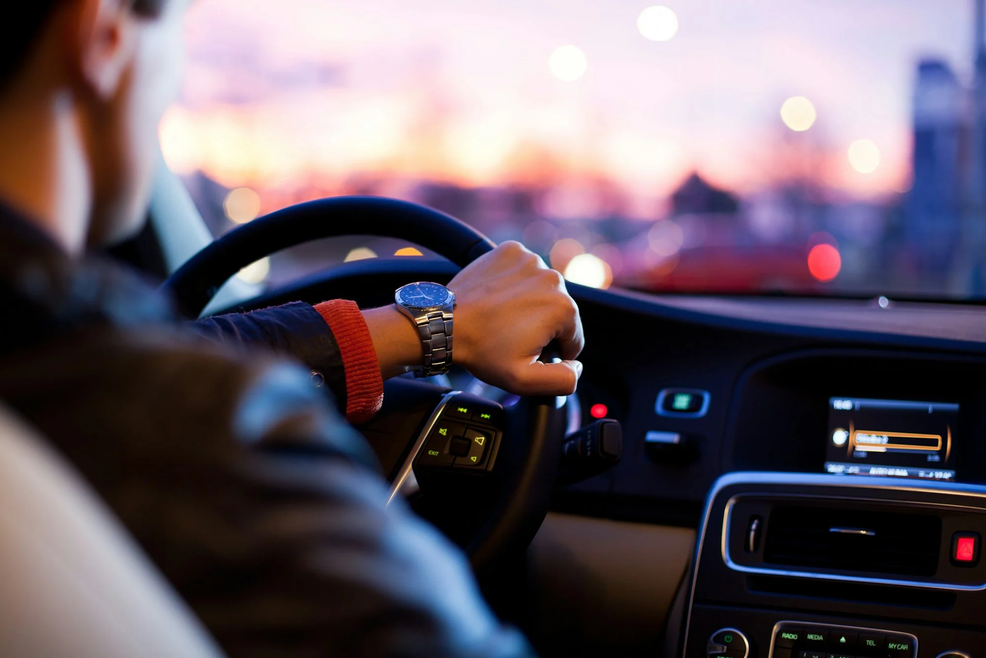 Driver hands on the steering wheel of a car at dusk, rideshare insurance Melbourne
